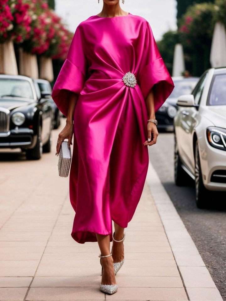 Woman in a rose red ruched satin boat-neck maxi dress with a crystal brooch