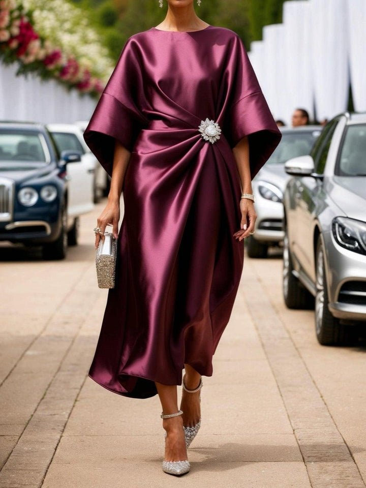Woman in a claret ruched satin boat-neck maxi dress with a crystal brooch
