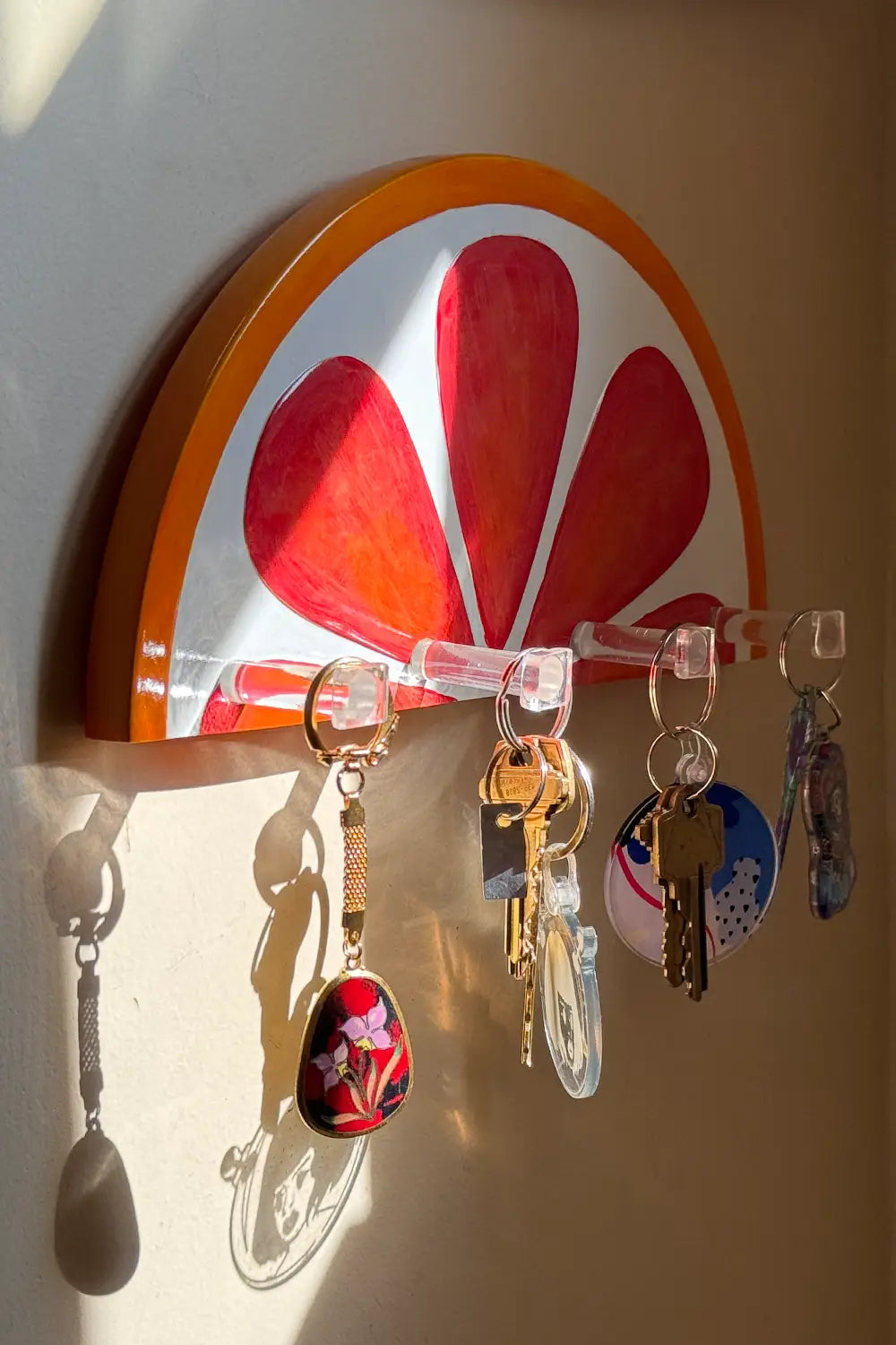 Blood orange wall sculpture showing four transparent key hooks