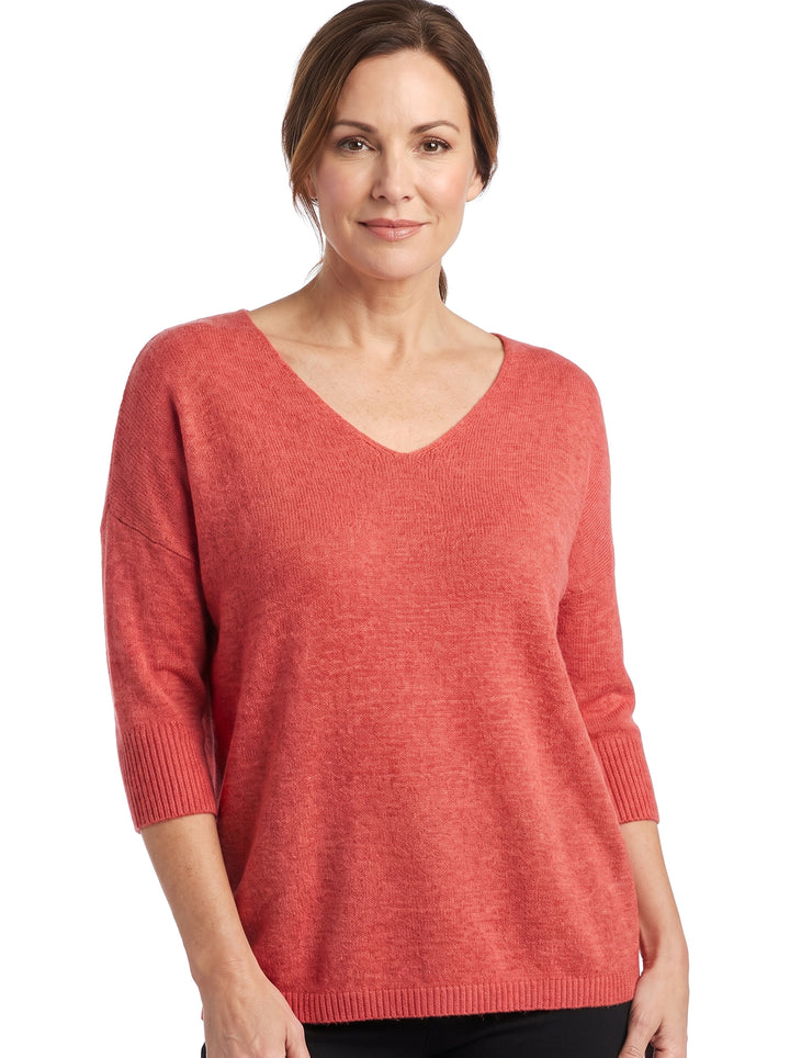 Woman wearing the Alma-Daphne relaxed knit V-neck blouse in coral red