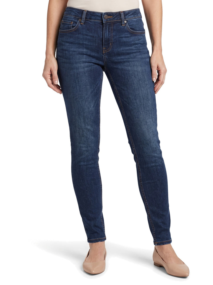 Woman wearing dark blue tapered skinny jeans, waist to feet studio shot